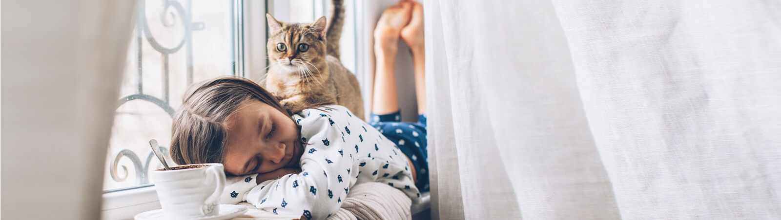 Eine Katze ruht auf dem Rücken eines schlafenden Mädchens.